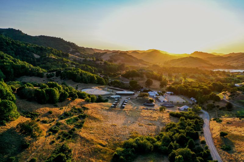 Golden-hour aerial overlooking Hindsight Farms, the valley, and the reservoir beyond