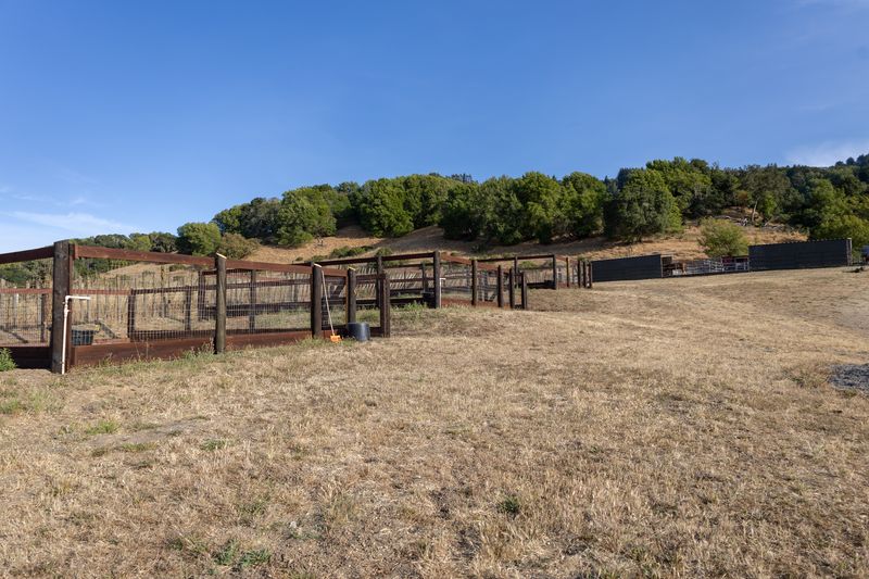 A long row of turnout pens follows the open hillside beneath a clear blue sky