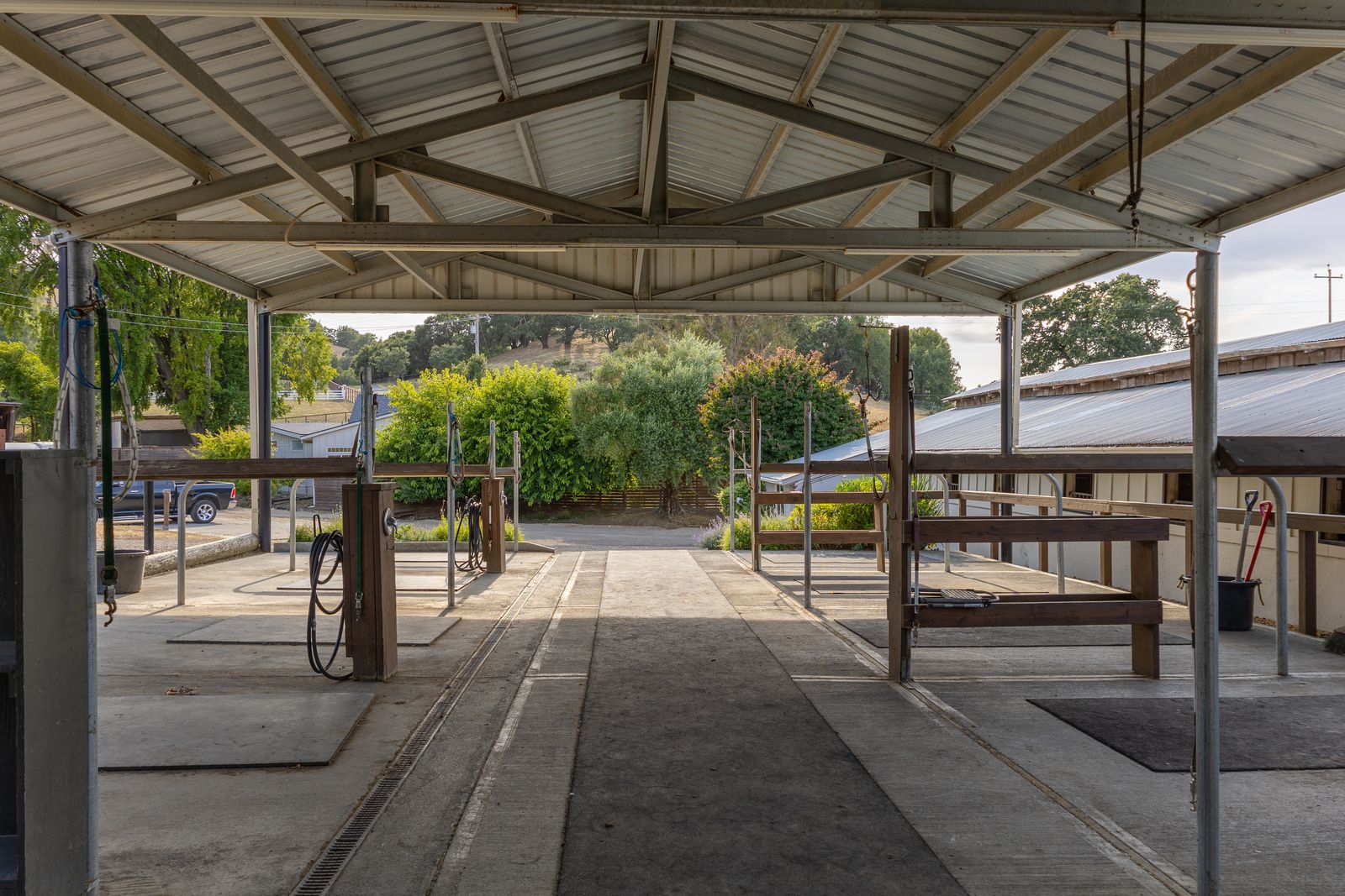 A covered wash and crosstie breezeway with hose reels and a view toward the hills.